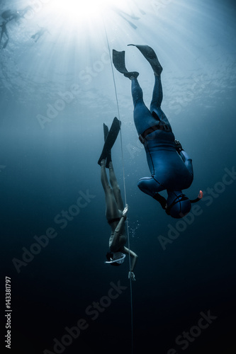 Free diver ascending along the rope in the depth