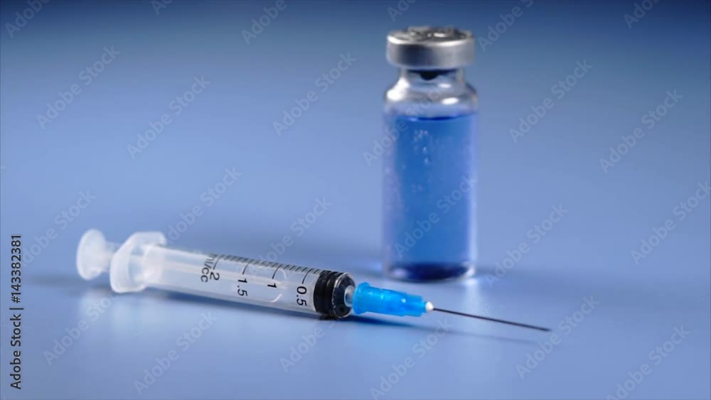 Macro view of ampoule and syringe with selective focus with ampoule on background. Concept of vaccination or injection. Macro view of ampoule and syringe with selective focus with ampoule on background. Concept of vaccination or injection.