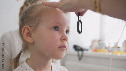 Cute child in ophthalmology clinic - optometrist diagnosis little blonde girl photo