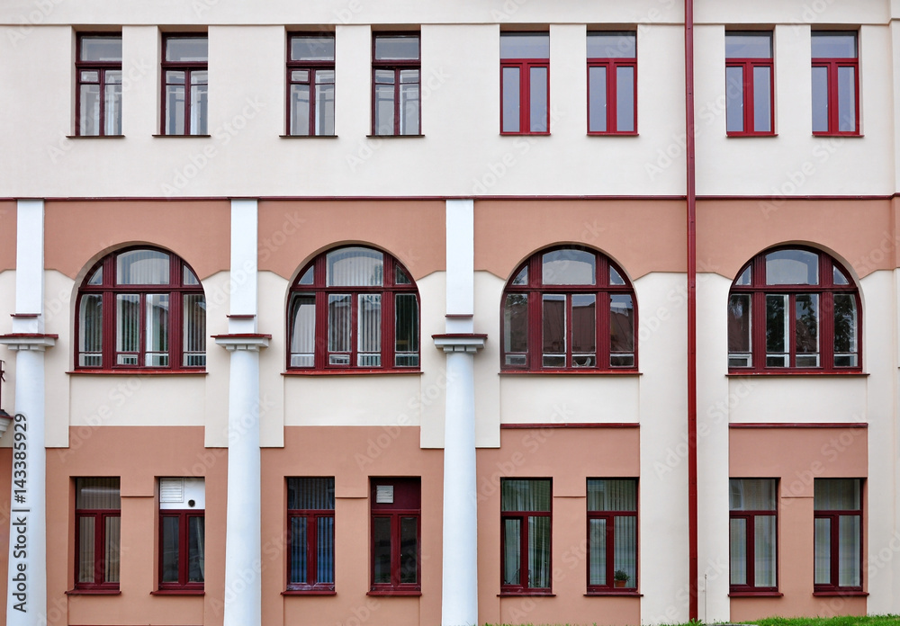 Ancient facade of the university building in Grodno, Belarus. Rows of arched and rectangular windows on a pink wall.