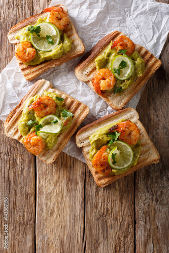 Delicious sandwiches with guacamole, shrimps and lime close-up. vertical top view