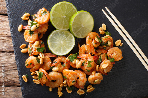 Sauteed shrimp with peanuts, lime and greens closeup on the table. horizontal top view