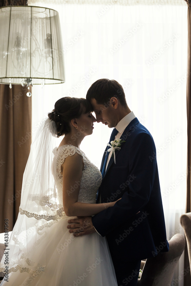 Groom and bride are kissing in hotel interior Groom and bride are kissing in hotel interior