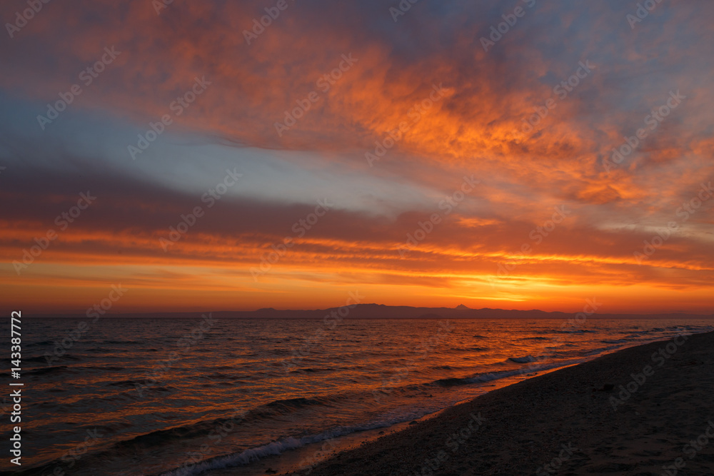 Spring orange dawn on the shore of the calm sea during the tide. Spring orange dawn on the shore of the calm sea during the tide.