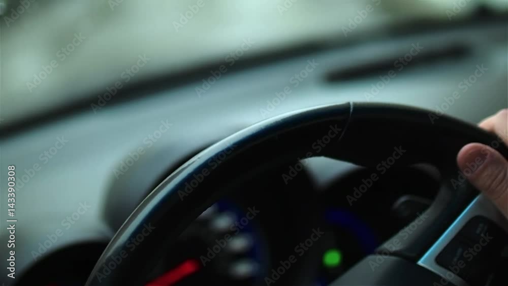 Male hands operate steering wheel of moving vehicle. Left side view. Close-up. Male hands operate steering wheel of moving vehicle. Left side view. Close-up.