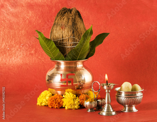 copper kalash with coconut and mango leaf with floral decoration, fruits, diya, sweet pedha,essential in hindu puja, front view, closeup