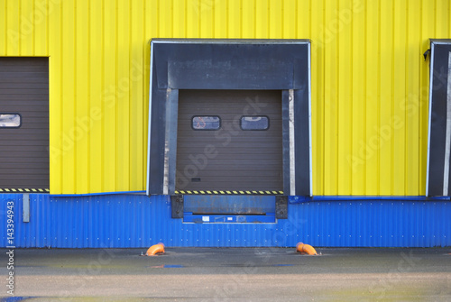 Facade of modern warehouse of yellow sandwich panels with airtight door gates (dock shelter). Front view.