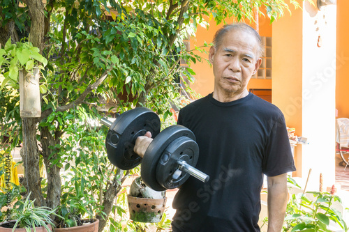 Old asia man with dumbbells. Person doing exercise outdoor. Strengthen the muscles. Your health is priceless. Hard work for a healthy lifestyle concept.
