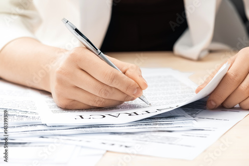 cropped view of businesswoman signing contract documents sitting at table