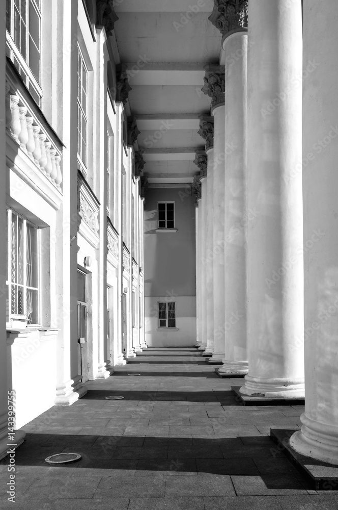 White colonnade of classical building with contrasting shadows. Architectural geometric black and white composition. White colonnade of classical building with contrasting shadows. Architectural geometric black and white composition.