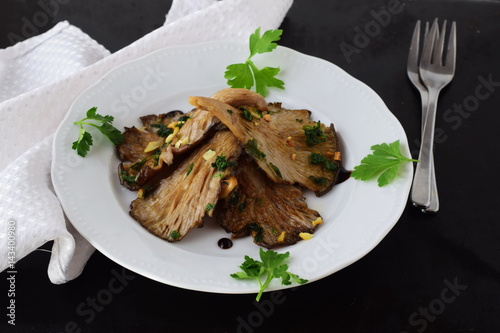 Fototapeta Naklejka Na Ścianę i Meble -  Fried oyster mushrooms with garlic, parsley in a balsamic glaze on a black background. Healthy eating concept.