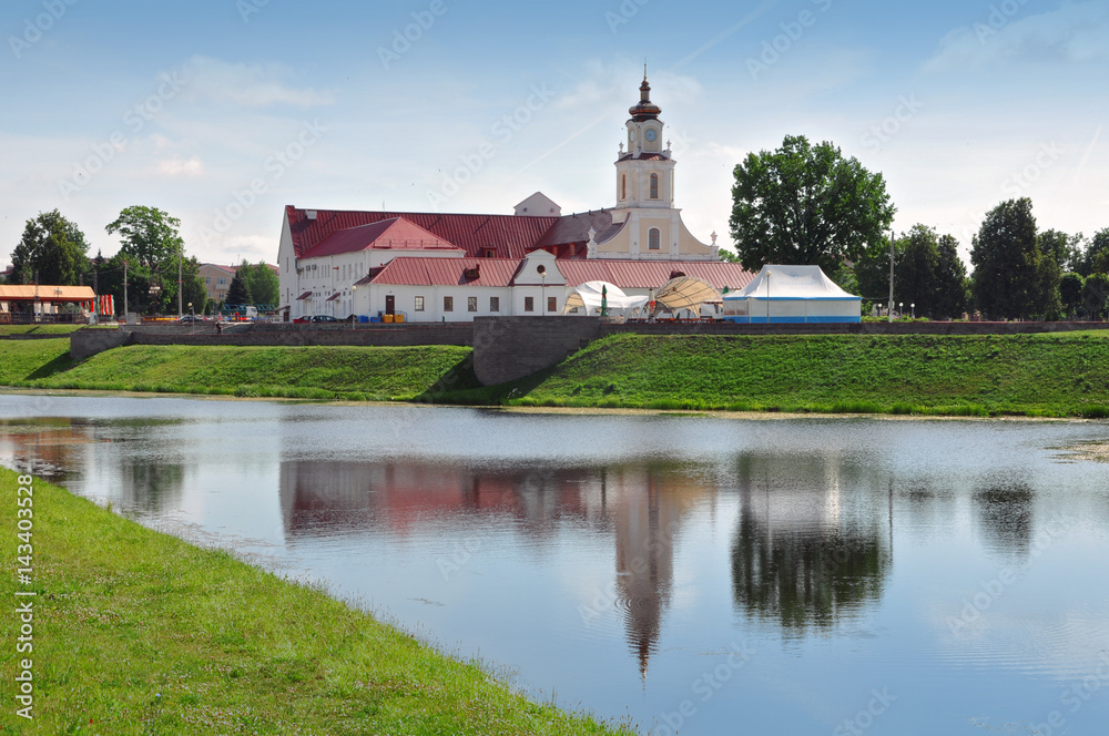 Old Town Hall in Orsha, Belarus. Tower in Baroque style with red roof reflected in water.