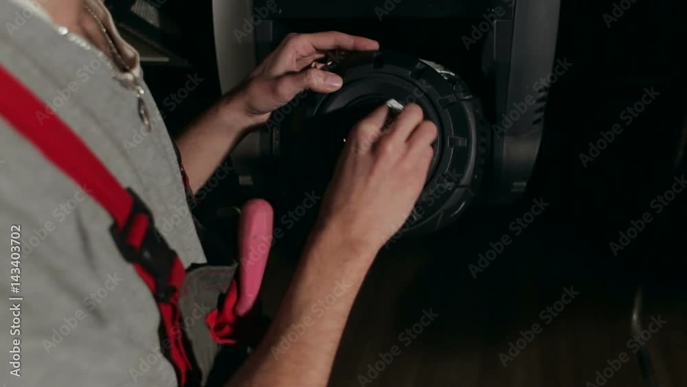 Mechanic wipes the lens on the light equipment behind the scenes. Mechanic wipes the lens on the light equipment behind the scenes.