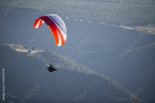 Paraglider flying over mountains.