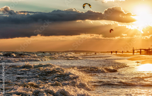 Scenic sunset on sandy Blaga Beach, Black Sea coast, Anapa, Russia. Beautiful landscape of seashore with surfing waves and flying kites. Kitesurf destination