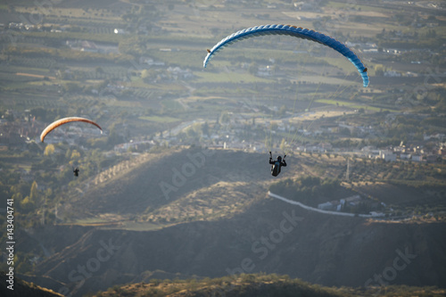 Paraglider flying over mountains.