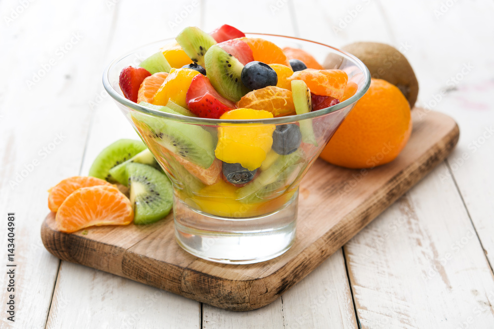 Fruit salad in crystal bowl on white wooden table.
Fruit salad in crystal bowl on white wooden table.