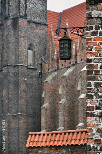 Antique metal street lamp on the background of medieval red brick church. Wroclaw  Poland. Selective focus.