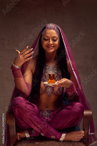 Eastern beautiful brunette woman in afghani pants, purdah and adornment have a tea armut