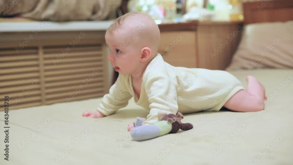 A small baby lies on a big bed, mom plays with a baby A small baby lies on a big bed, mom plays with a baby
