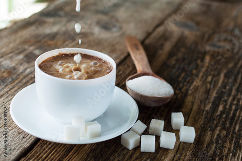 cup of coffee with milk and sugar spoon on the table