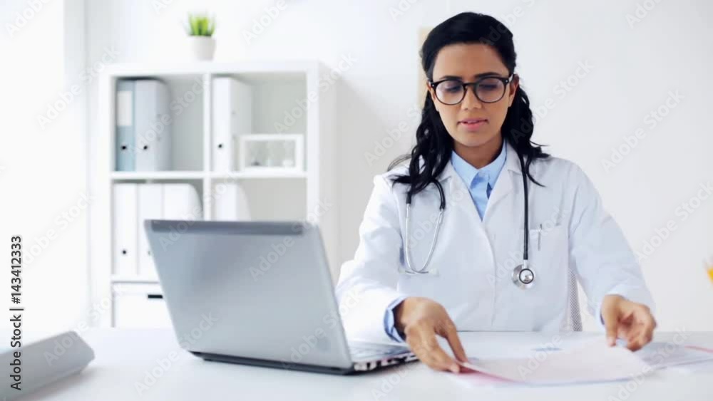 female doctor with laptop and papers at hospital