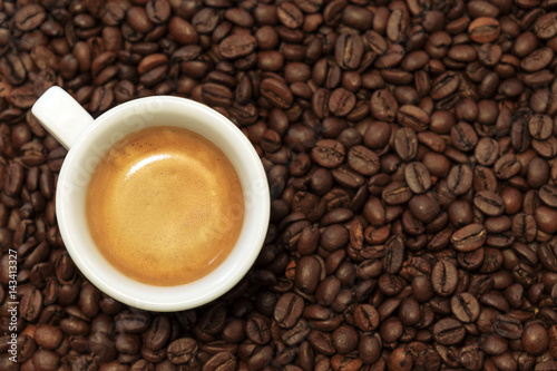 White cup of espresso on coffee beans background
