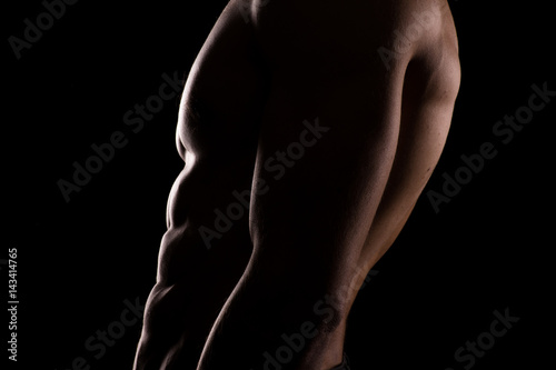 Close up of a sports man's chest. Muscular man on a dark background