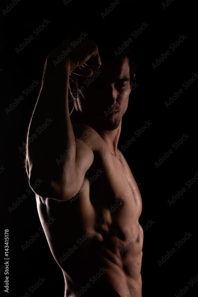 Muscular and defined six pack abs on handsome male model posing on black background