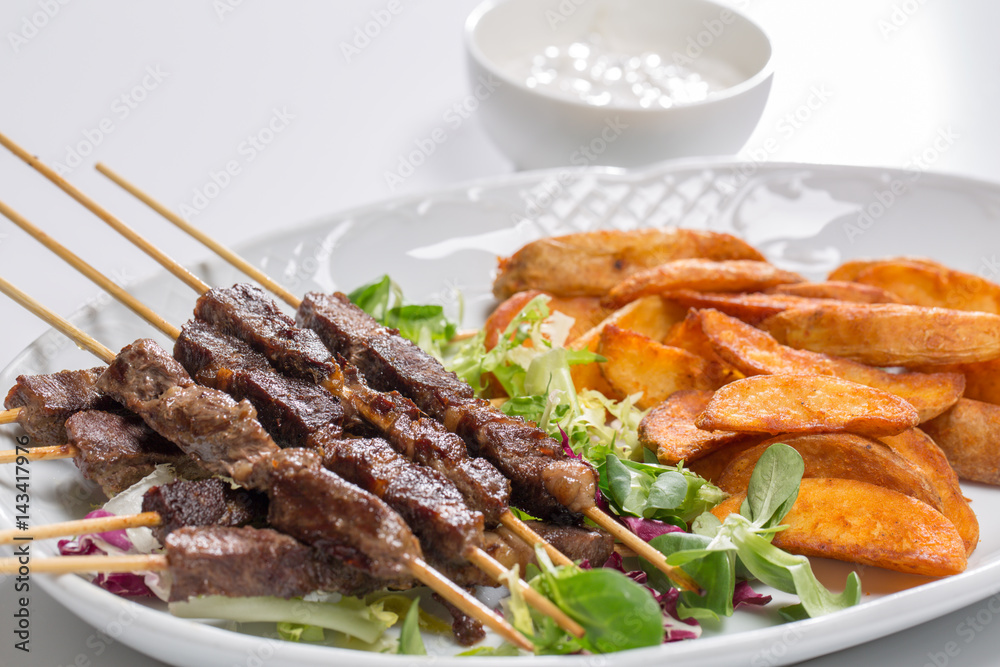 Lamb skewers on salad with wedges potatoes
