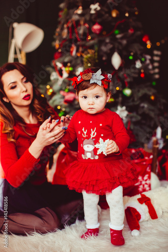 Attaractie young mother poses with her little girl before green Christmas tree