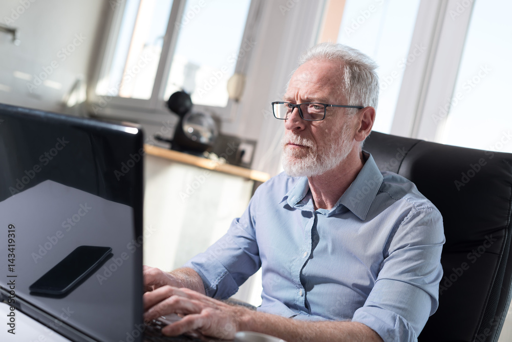 Portrait of senior businessman working on laptop, hard light Portrait of senior businessman working on laptop, hard light