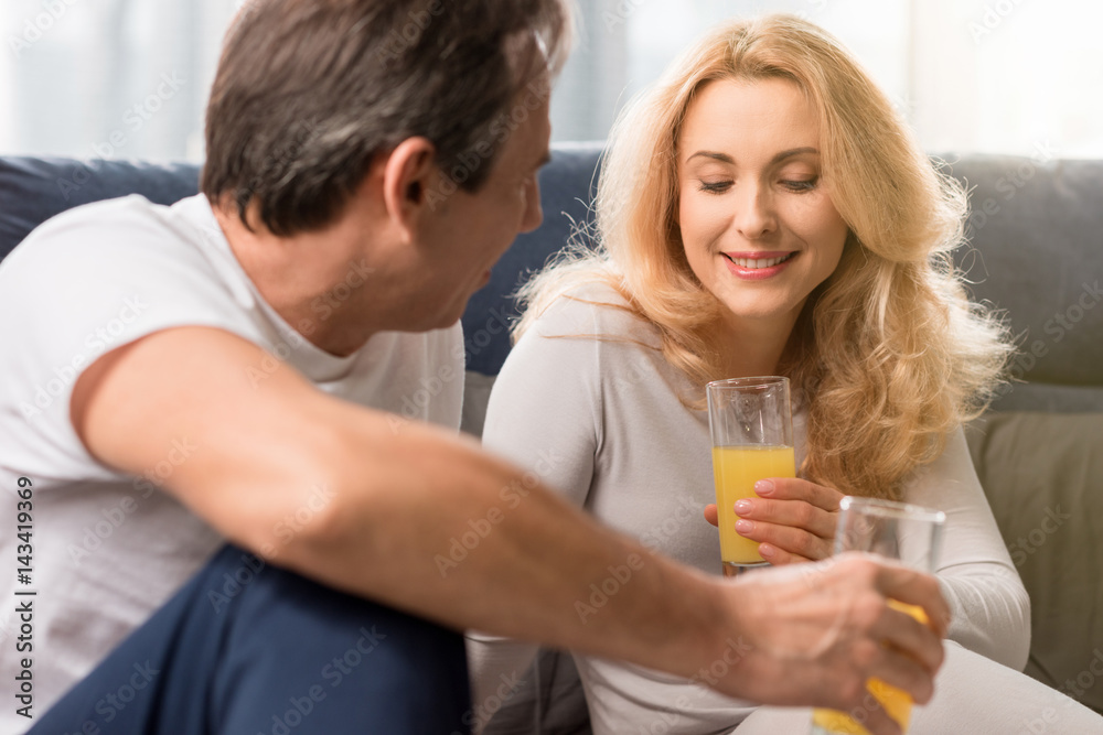 Happy middle aged couple holding glasses with orange juice on bed Happy middle aged couple holding glasses with orange juice on bed