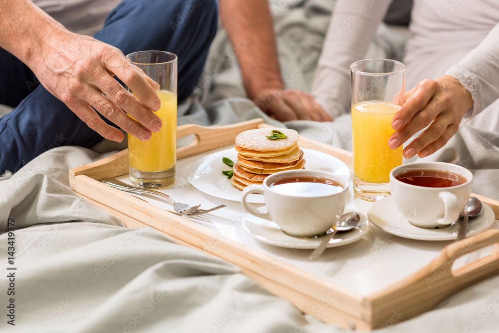 Cropped shot of couple having breakfast together in bed Cropped shot of couple having breakfast together in bed