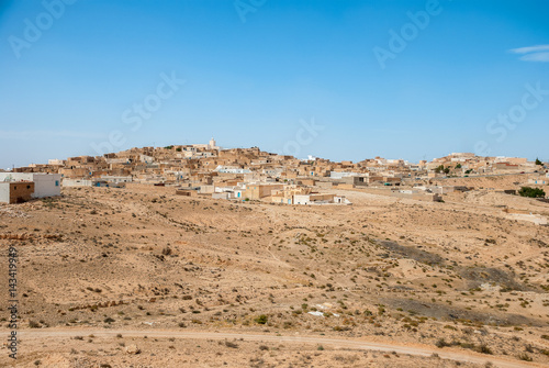 Traditional Arabian city on sand dunes in the desert photo