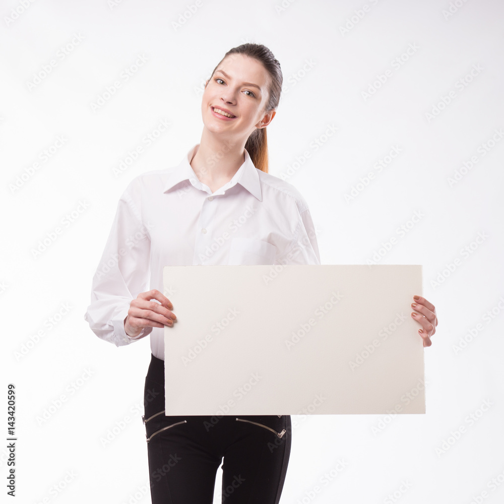 Young happy woman showing presentation, pointing on placard over gray background Young happy woman showing presentation, pointing on placard over gray background