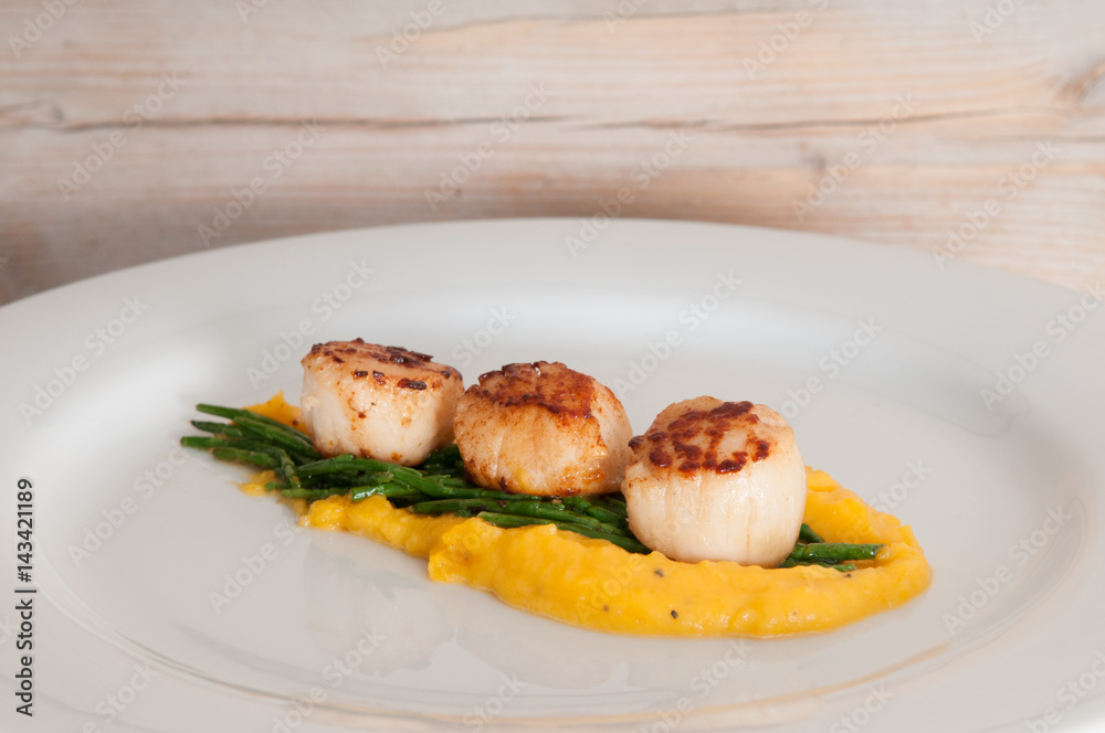 gourmet seafood dish of scallops and asparagus on a white plate