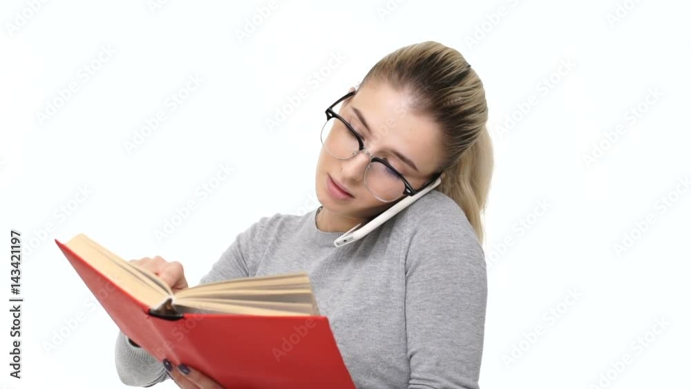 Beautiful young blonde woman talking on mobile phone and checking her diary isolated over white Beautiful young blonde woman talking on mobile phone and checking her diary isolated over white