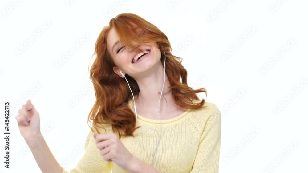 Happy joyful girl with long red curly hair listening to music with earphones and playing on invisible drums isolated Happy joyful girl with long red curly hair listening to music with earphones and playing on invisible drums isolated