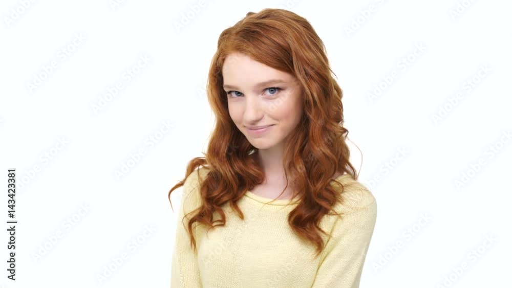 Playful young woman with red long curly hair posing and flirting with camera isolated over white Playful young woman with red long curly hair posing and flirting with camera isolated over white