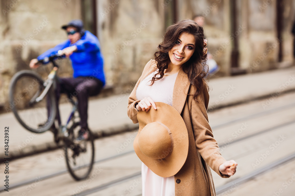 Woman in pink dress and beige coat poses on tramways Woman in pink dress and beige coat poses on tramways