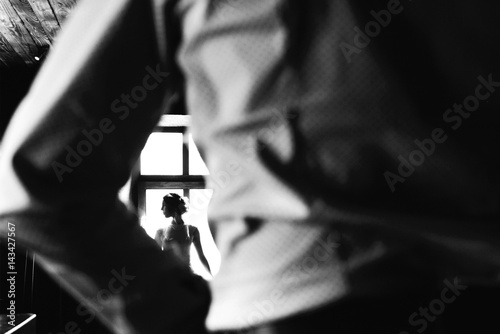 Look from behind man s back at stunning woman sitting before bright window