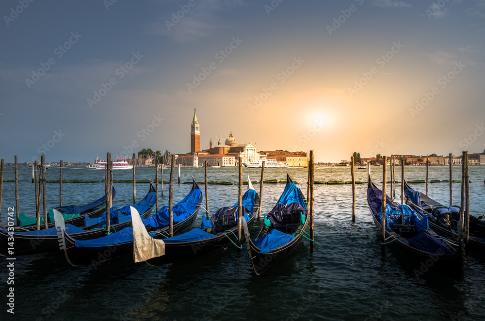 Pier for docking gondolas in Venice, Italy at sunset. In the background is Church of San Giorgio Maggiore. 