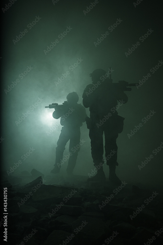Black silhouettes of pair of soldiers in the smoke haze moving in battle operation. Back light Black silhouettes of pair of soldiers in the smoke haze moving in battle operation. Back light