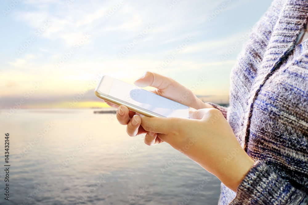 Woman using her Mobile Phone on the beach Background.