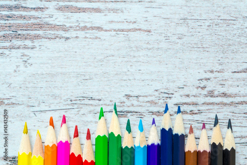 Colored multicolored pencils close up macro down on a vintage wooden background, wooden worn boards with cracks. Top view. photo