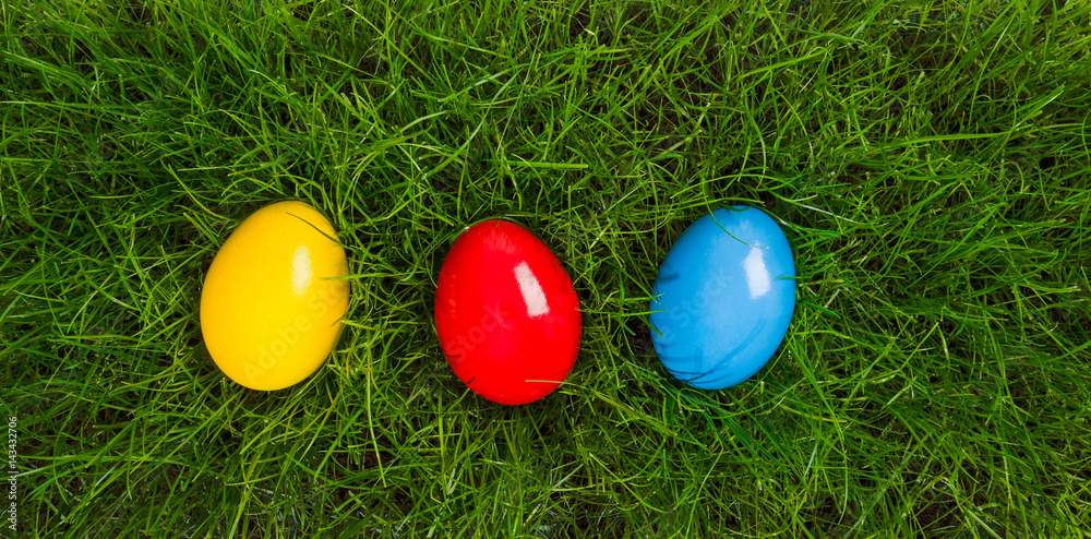 easter eggs in yellow, red and blue lying in grass in birds eye view easter eggs in yellow, red and blue lying in grass in birds eye view