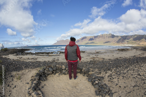 Ragazzo guarda il panorama della spiaggia di Famara nella parte nord-occidentale dell'isola di Lanzarote alle Canarie in Spagna. L'isola è stata nominata riserva della biosfera dall'UNESCO photo