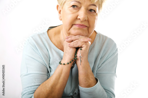 Starsza kobieta trzyma różaniec 