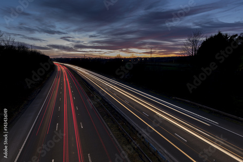 A UK motorway  at sunset  with light trails created by the traffic on the road